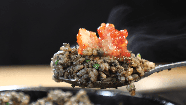 Spoonful of stone pot bibimbap topped with steaming marinated crab.