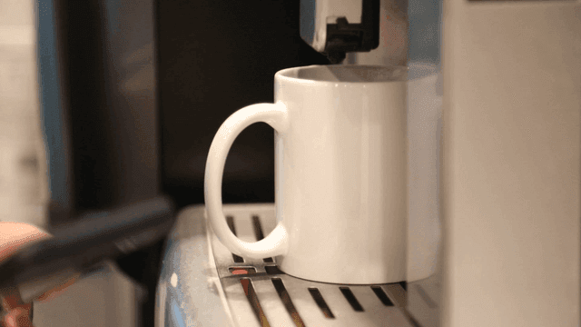 커피 머신이 흰색 머그잔에 커피를 내리는 장면