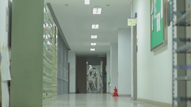 사물함과 게시판이 있는 복도를 걸어가는 대학생