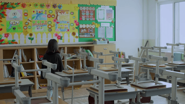 Child looking at the bulletin board while cleaning the classroom