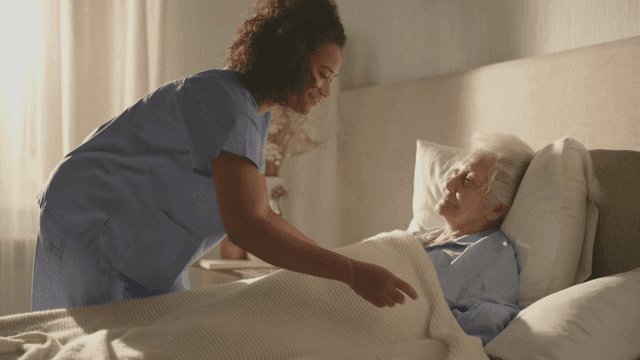 여성 노인 환자 이불을 덮어주는 간호사