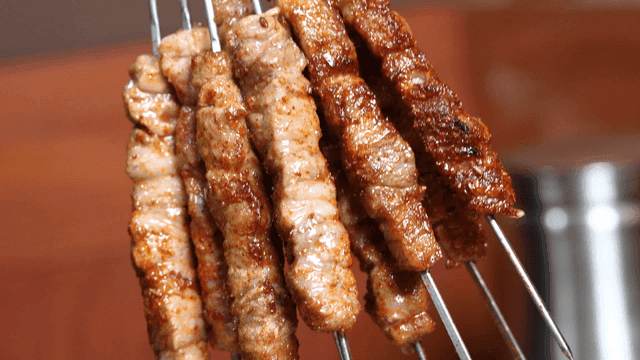 Grilled lamb skewers being lifted