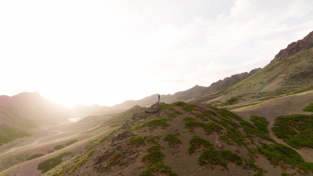 햇빛을 받으며 산 위에 서 있는 사람