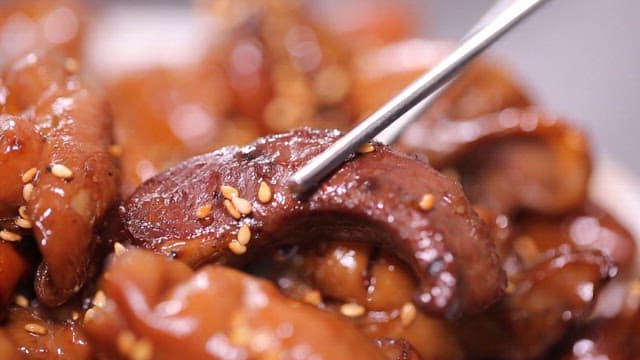 Chopsticks holding glazed seasoned pork intestines