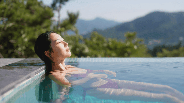 Woman relaxing by swimming pool while looking at mountain view