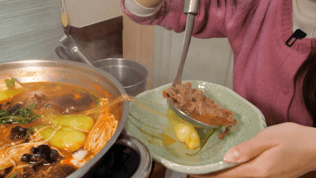 Person putting hot beef bulgogi stew into bowl