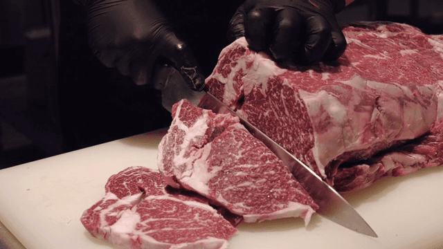 Slicing a large piece of raw beef