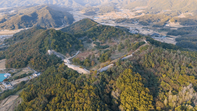 Aerial view of mountain with lush forest and fortress
