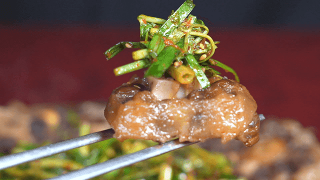 Chopsticks holding boiled oxtail with green onions and sauce