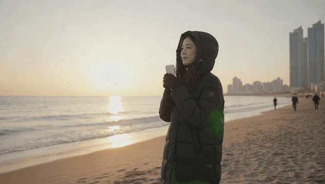 여성이 해변에서 일출을 즐기는 모습