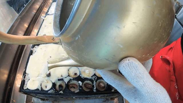Pouring batter into takoyaki molds