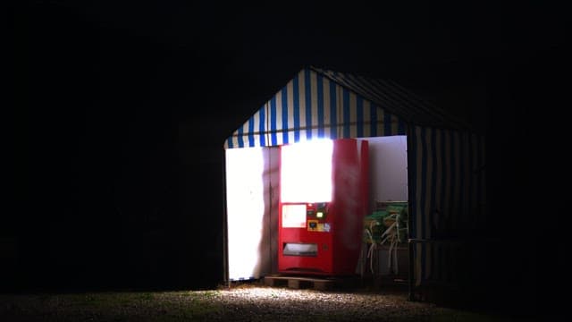 밤에 천막 아래 자판기를 사용하는 사람