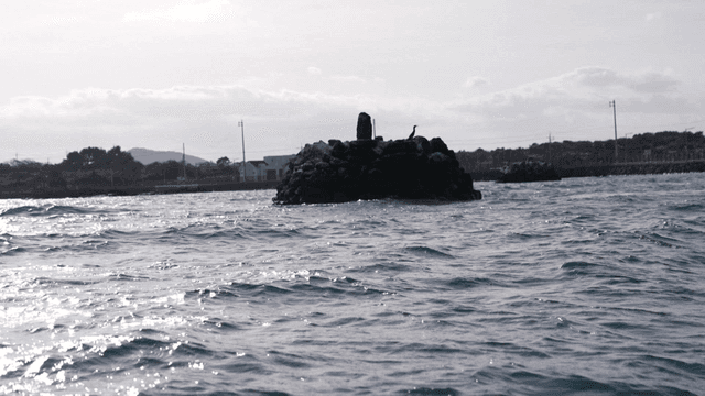Rocky island in sea under sun