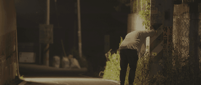 Person leaning on a pole at night
