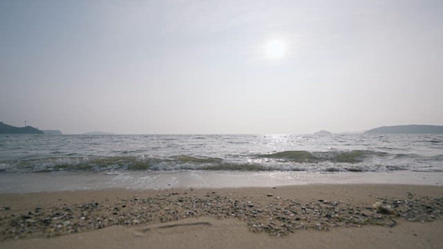 강렬한 태양 아래 파도가 밀려오는 평화로운 해변