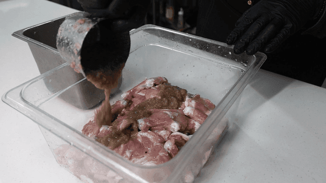 Scene of marinating chicken with sauce in kitchen