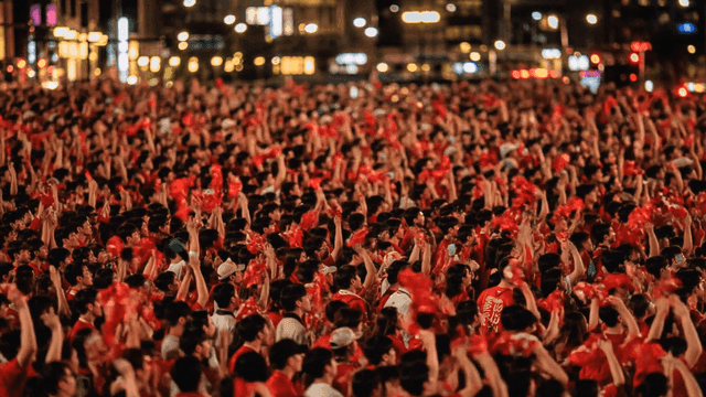 Cheering by massive crowd gathered in city at night