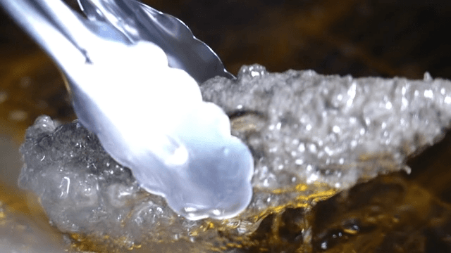 집게로 뜨거운 기름에 튀겨진 검은 고추튀김