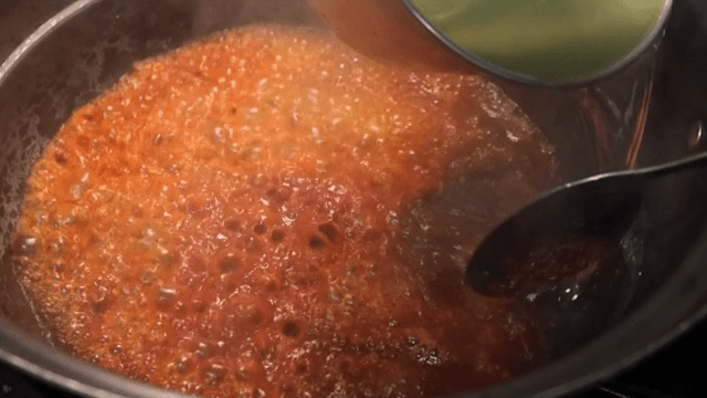Broth being poured into a pot with spices