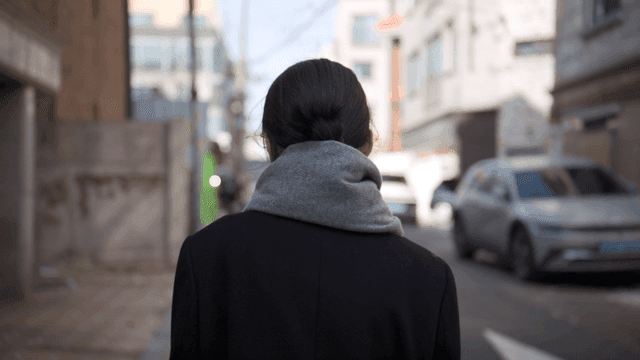 Back view of woman walking down narrow alley