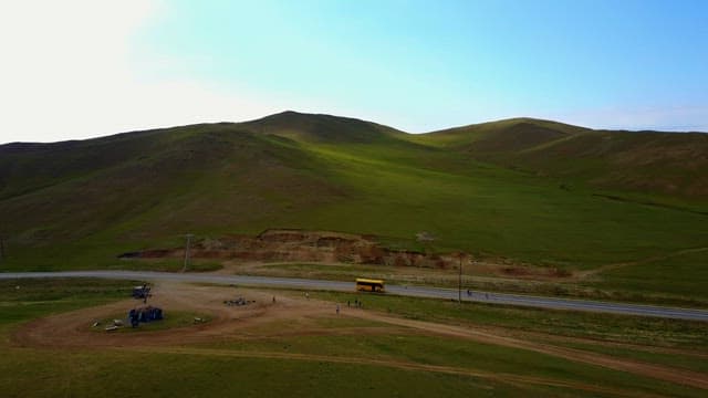 Yellow bus on the road with green hills