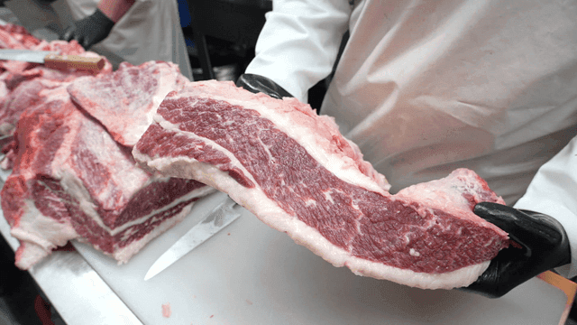 Lifting prepared fresh beef in butcher shop by butcher