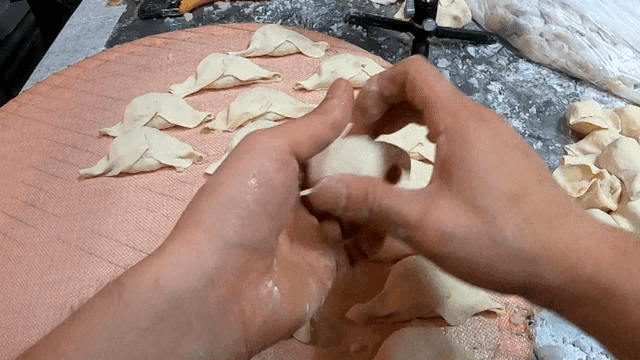 쟁반 위에서 만두 모양을 빠르게 접어내는 손