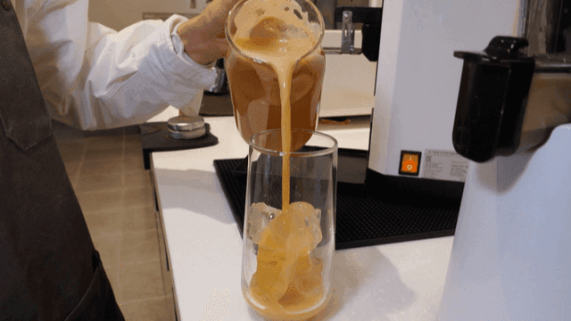 Barista pouring coffee into glass filled with ice