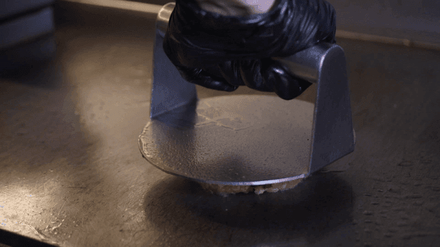 Raw burger patty pressed on grill