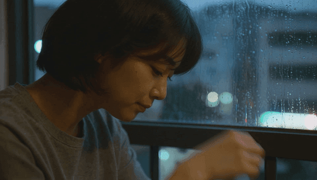 Woman drinking soju by the window on a rainy evening