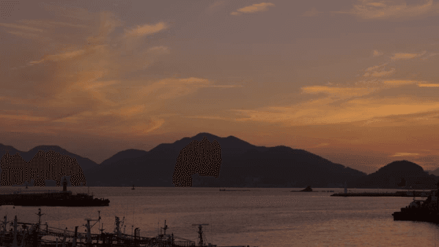 Sunset over a calm sea with mountains and fishing boats