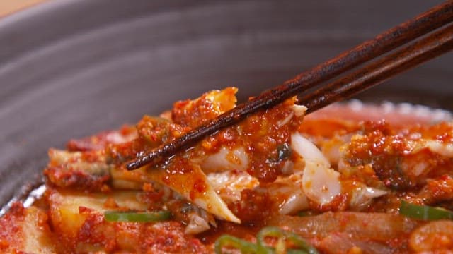 Fish boiled in spiced soy sauce being held with chopsticks