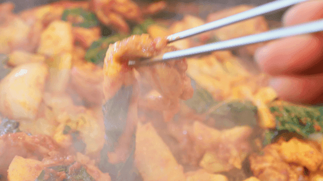 Chopsticks picking up steaming hot spicy dakgalbi