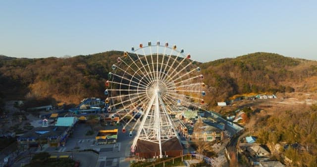 Ferris wheel in an amusement park with mountainous background