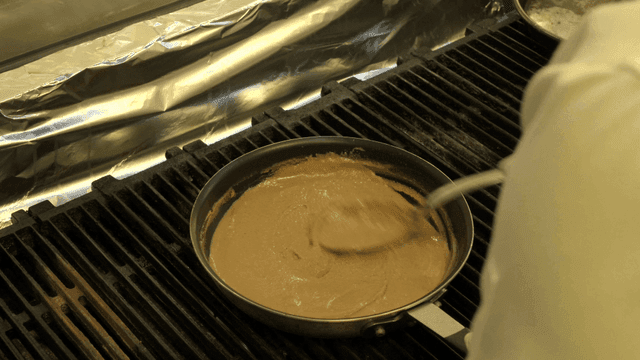 Chef stirring sauce in pan on stove