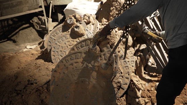 Worker handling manhole covers in a factory