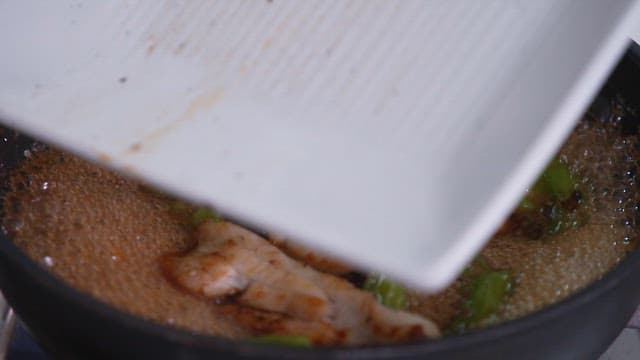 Hairtail being cooked in a pan with sauce