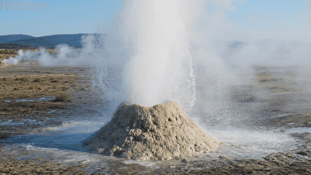 Geysers erupting in wide landscape.