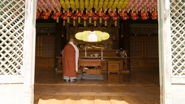 Monk in a temple with a golden Buddha statue