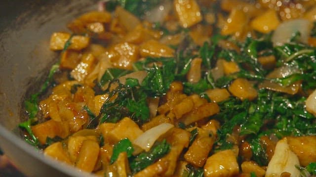 야외 불 위 프라이팬에서 시금치와 참치를 볶아 만드는 요리