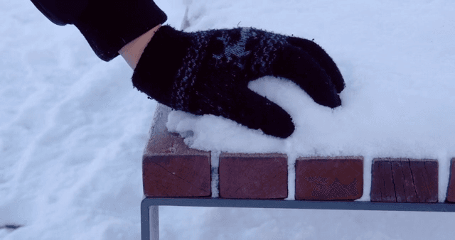 벤치 위의 눈을 만지는 장갑 낀 손