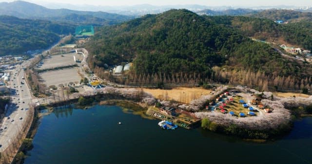 Amusement park surrounded by nature with a ferris wheel next to a lake