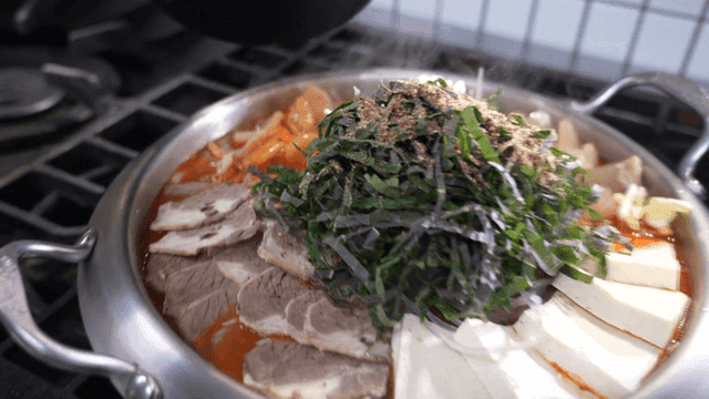 Spicy beef hot pot topped with tofu and perilla leaves