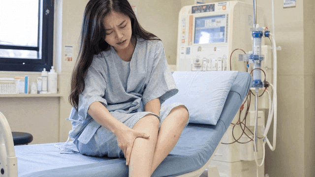 Female patient sitting on bed wearing hospital gown