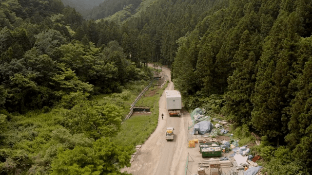 울창한 숲 옆으로 공사 물품들이 놓여진 도로