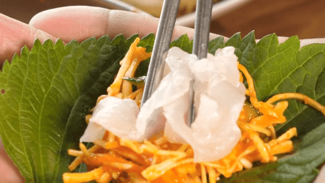 깻잎에 채소 무침과 신선한 회를 싸먹는 모습