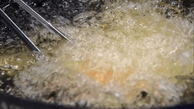 Deep frying whole chicken in hot oil