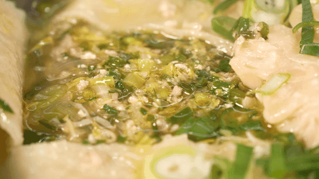 Boiling dumpling soup full of green onions