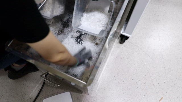 공장에서 플라스틱 펠릿을 퍼서 옮기는 작업자