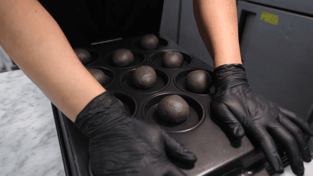 베이킹 트레이에 둥근 반죽을 눌러 넣는 제빵사